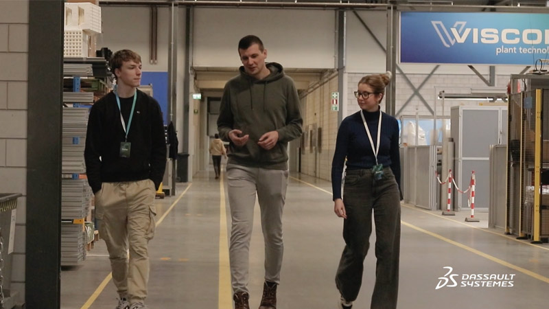 製造工場のフロアで話をしている3人の従業員