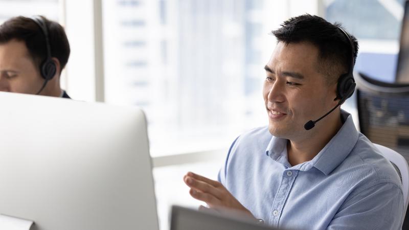 man with headset seated at a computer providing virtual tech support