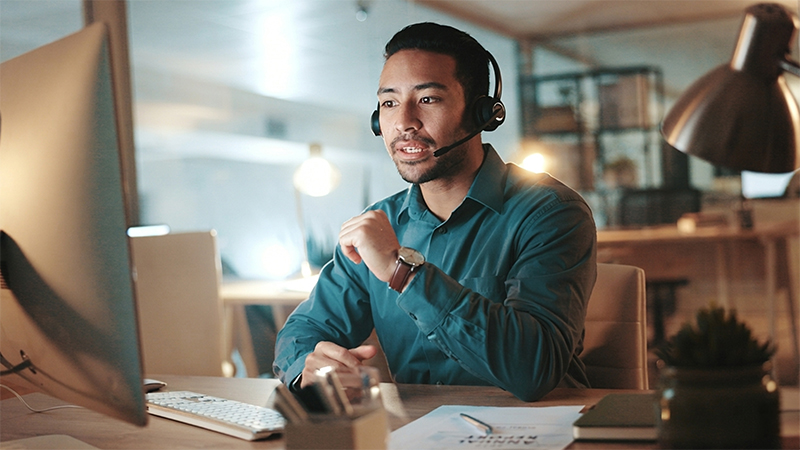 Worker with headphones in front of computer monitor