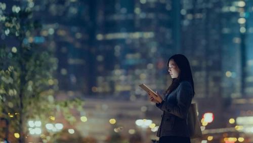 Frau in der Stadt bei Nacht mit Laptop