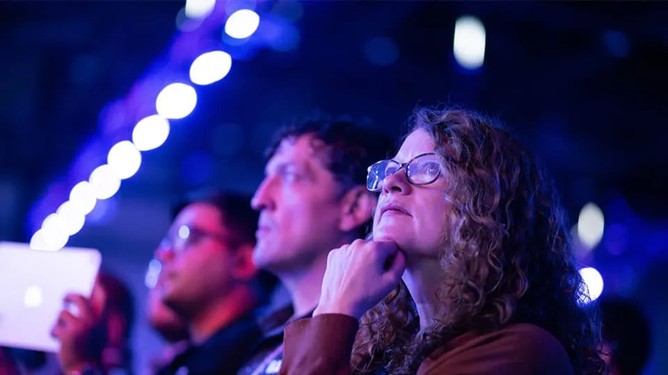 3DEXPERIENCE World 2025 attendees watching a presentation, woman in the foreground