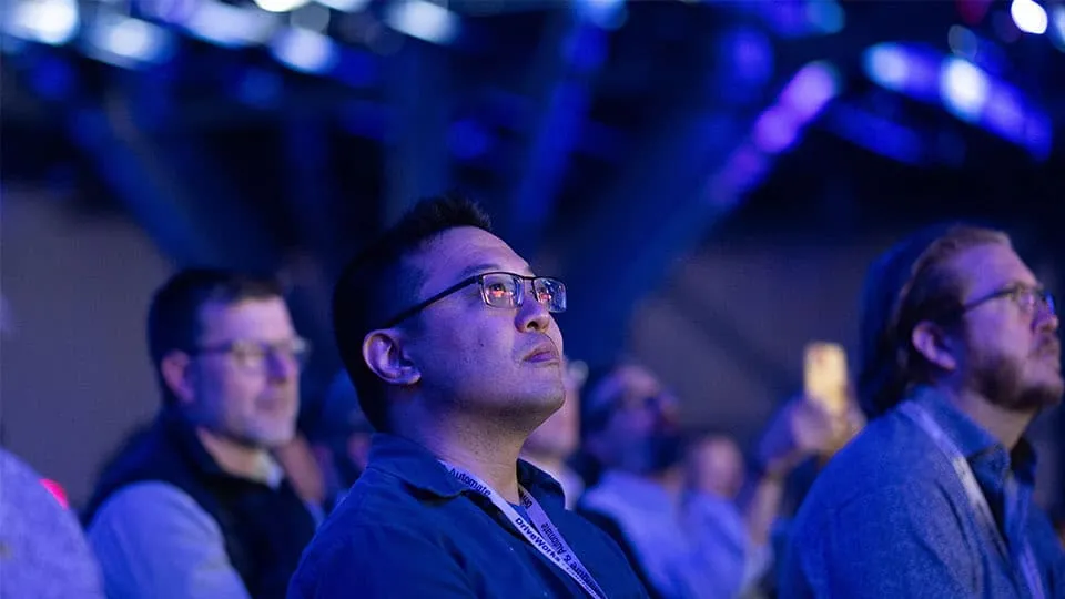 3DEXPERIENCE World 2025 attendees watching a presentation in darkened room