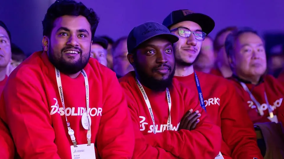 3DEXPERIENCE World 2025 attendees in SOLIDWORKS sweatshirts watching a presentation