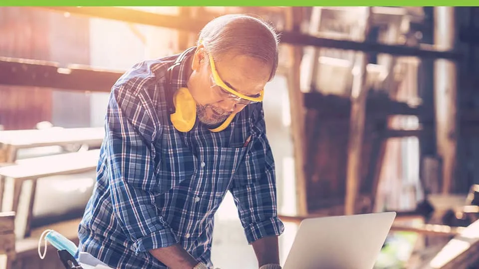 Man working on laptop in a manufacturing facility