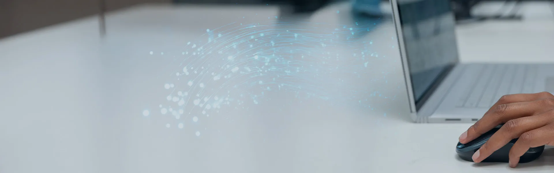 A person's hand on a computer mouse near a laptop with graphic depiction of lines of energy waves