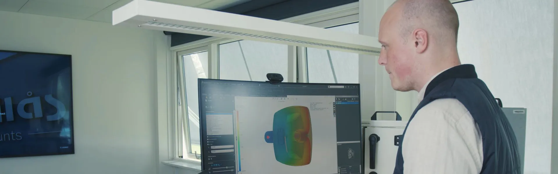 Person working on SOLIDWORKS 3D model with simulation data