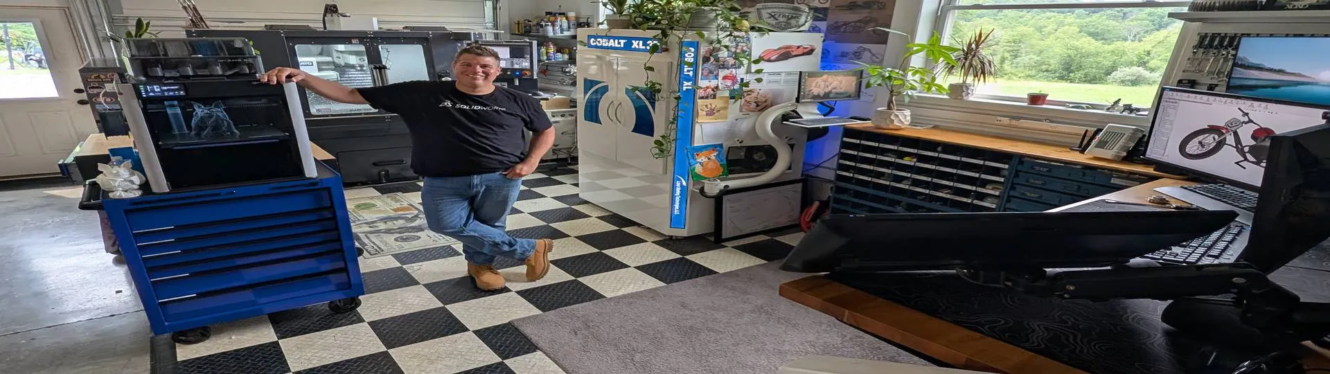 Jason Pohl in his workshop with his 3D printer and CNC machine, projects designed in SOLIDWORKS for Makers