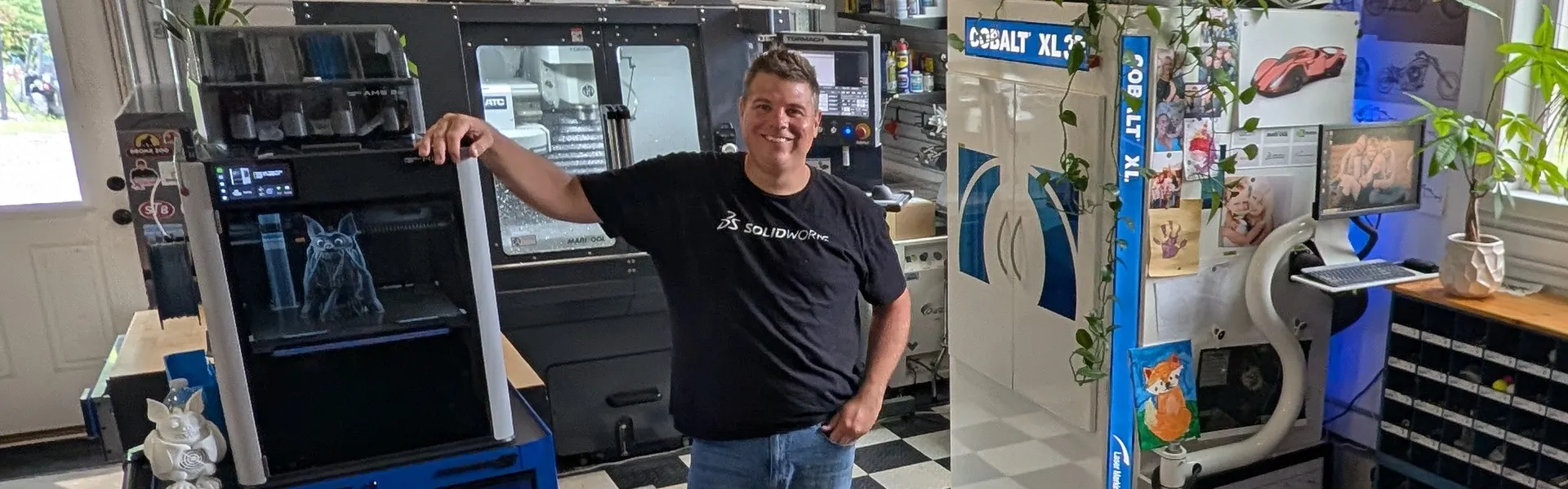 Jason Pohl in his workshop with his 3D printer and CNC machine, projects designed in SOLIDWORKS for Makers